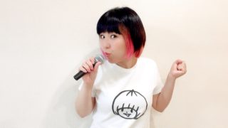 マイクを持って歌っているおかっぱミユキの写真。楽しそうな表情で、踊っている。