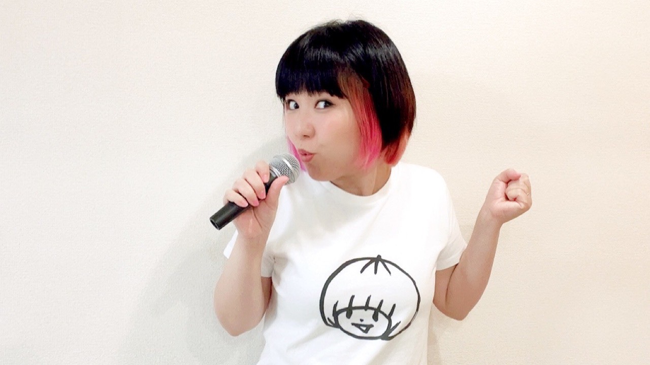 マイクを持って歌っているおかっぱミユキの写真。楽しそうな表情で、踊っている。