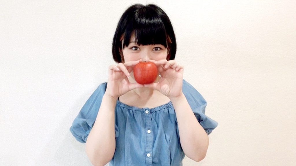 リンゴを持っているおかっぱミユキの写真。とても赤くておいしそうな林檎だ。