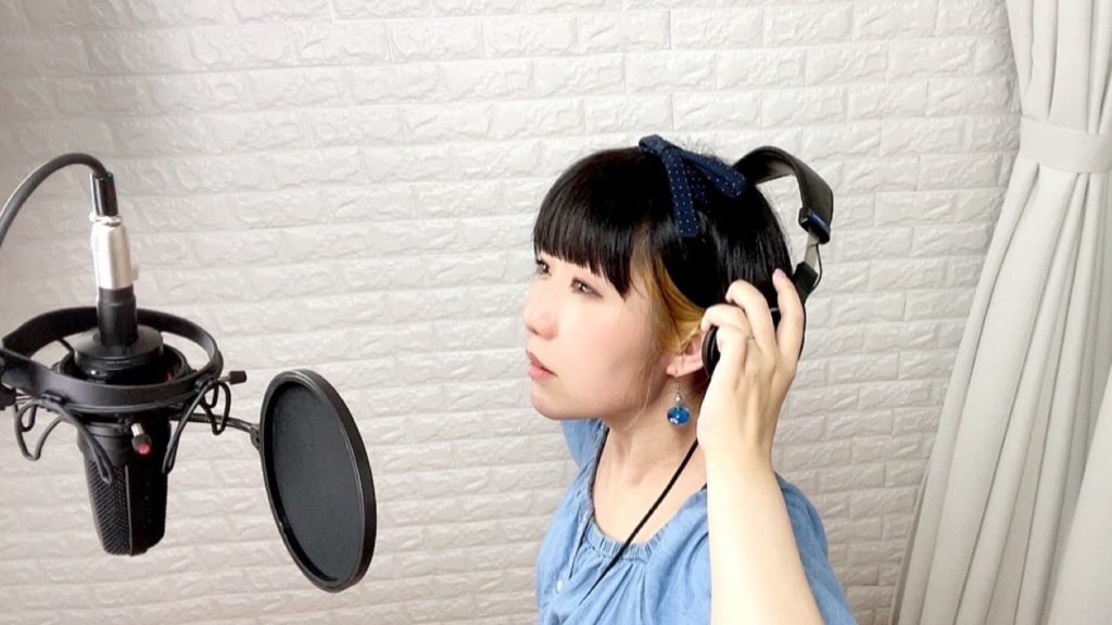 ボーカルレコーディング中のおかっぱミユキの写真。これから歌のレコーディングをするのか、ヘッドフォンを着けようとしている。